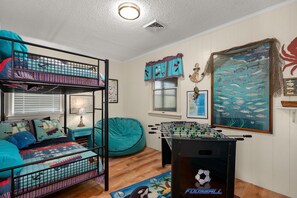 A bunk bed with a blue and red patterned bedspread, a teal bean bag chair, a foosball table, and a wall mural of fish. - 412 - Oceanfront w/ gorgeous views and open beach (Nags Head)