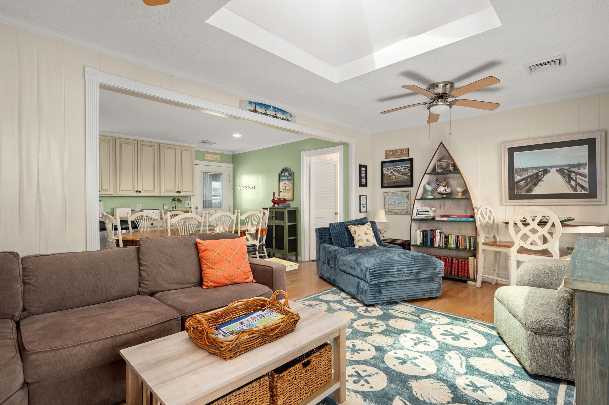 A spacious living area with a sofa, a blue armchair, a coffee table, and a ceiling fan.