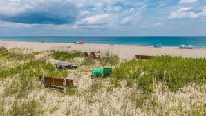 A beach with sand dunes, beach umbrellas, and a wooden bench. - 412 - Oceanfront w/ gorgeous views and open beach (Nags Head)