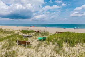 A beach with sand dunes, beach umbrellas, and a wooden bench. - 412 - Oceanfront w/ gorgeous views and open beach (Nags Head)