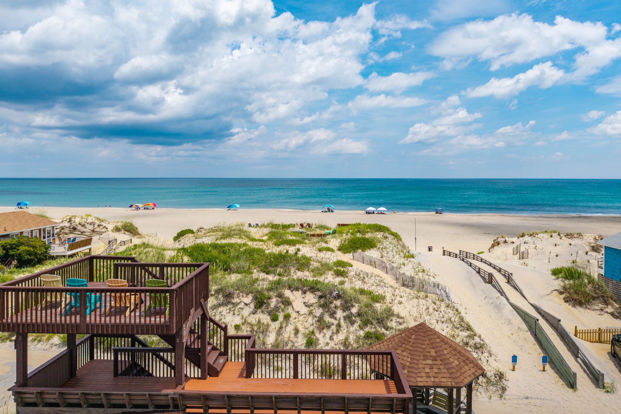 A beach with a wooden deck, a small hut, and a clear view of the ocean.