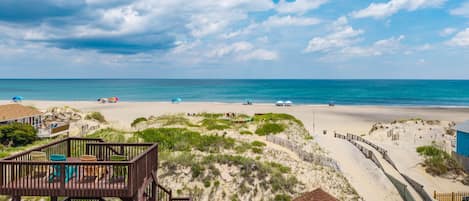 A beach with a wooden deck, a small hut, and a clear view of the ocean.