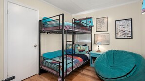 A bunk bed room with a desk and bean bag, a door, and wall decorations. - 412 - Oceanfront w/ gorgeous views and open beach (Nags Head)