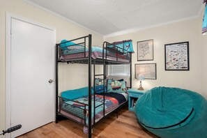 A bunk bed room with a desk and bean bag, a door, and wall decorations. - 412 - Oceanfront w/ gorgeous views and open beach (Nags Head)