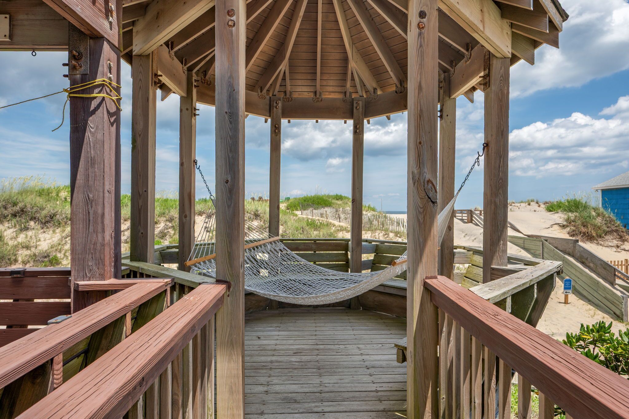 A wooden deck with a hammock and a view of the beach.