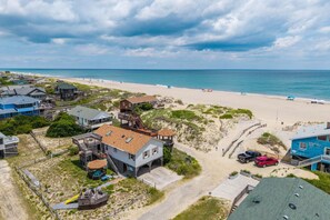A coastal residential area with beachfront properties, including houses with decks and a beach access path. - 412 - Oceanfront w/ gorgeous views and open beach (Nags Head)