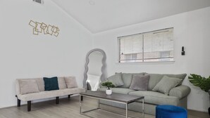 Een moderne woonkamer met een bank, een salontafel en een blauwe poef.