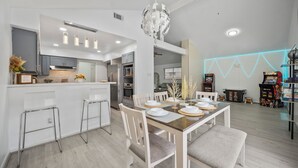 Een moderne keuken met een centraal eiland, barstoelen en een eethoek met een tafel gedekt voor vier personen.