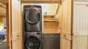A compact laundry area with two stacked washers and a small cabinet. - New Luxury Smoky Mountain Cabin, Hot Tub, Fire Pit, Mountain Views & Easy Access (SEVIERVILLE)