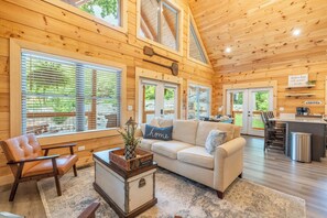 L’intérieur chaleureux d’un chalet avec des murs en bois, un canapé, une table basse et un coin cuisine.