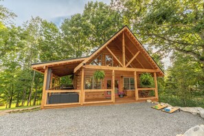 Eine Holzhütte mit Veranda, großen Fenstern und einem Schotterweg.