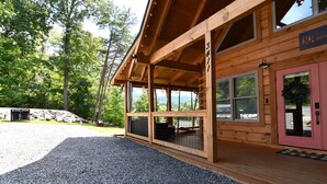A wooden cabin with a covered porch, a gravel driveway, and a view of the surrounding forest. - New Luxury Smoky Mountain Cabin, Hot Tub, Fire Pit, Mountain Views & Easy Access (SEVIERVILLE)