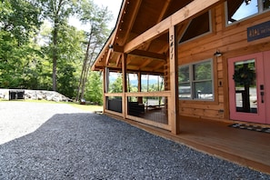 A wooden cabin with a covered porch, a gravel driveway, and a view of the surrounding forest. - New Luxury Smoky Mountain Cabin, Hot Tub, Fire Pit, Mountain Views & Easy Access (SEVIERVILLE)