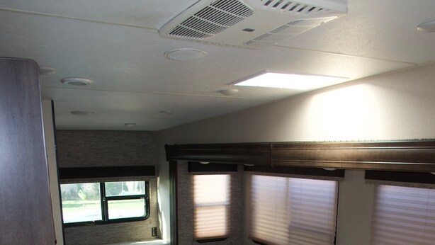 Interior compacto de una caravana con kitchenette, zona de estar y ventana.