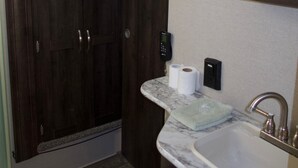 Un baño con tocador de madera oscura, encimera de mármol, lavabo y espejo.