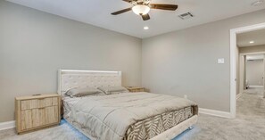 Una camera da letto con un letto, un comodino, una ventola a soffitto e un pavimento rivestito di moquette.