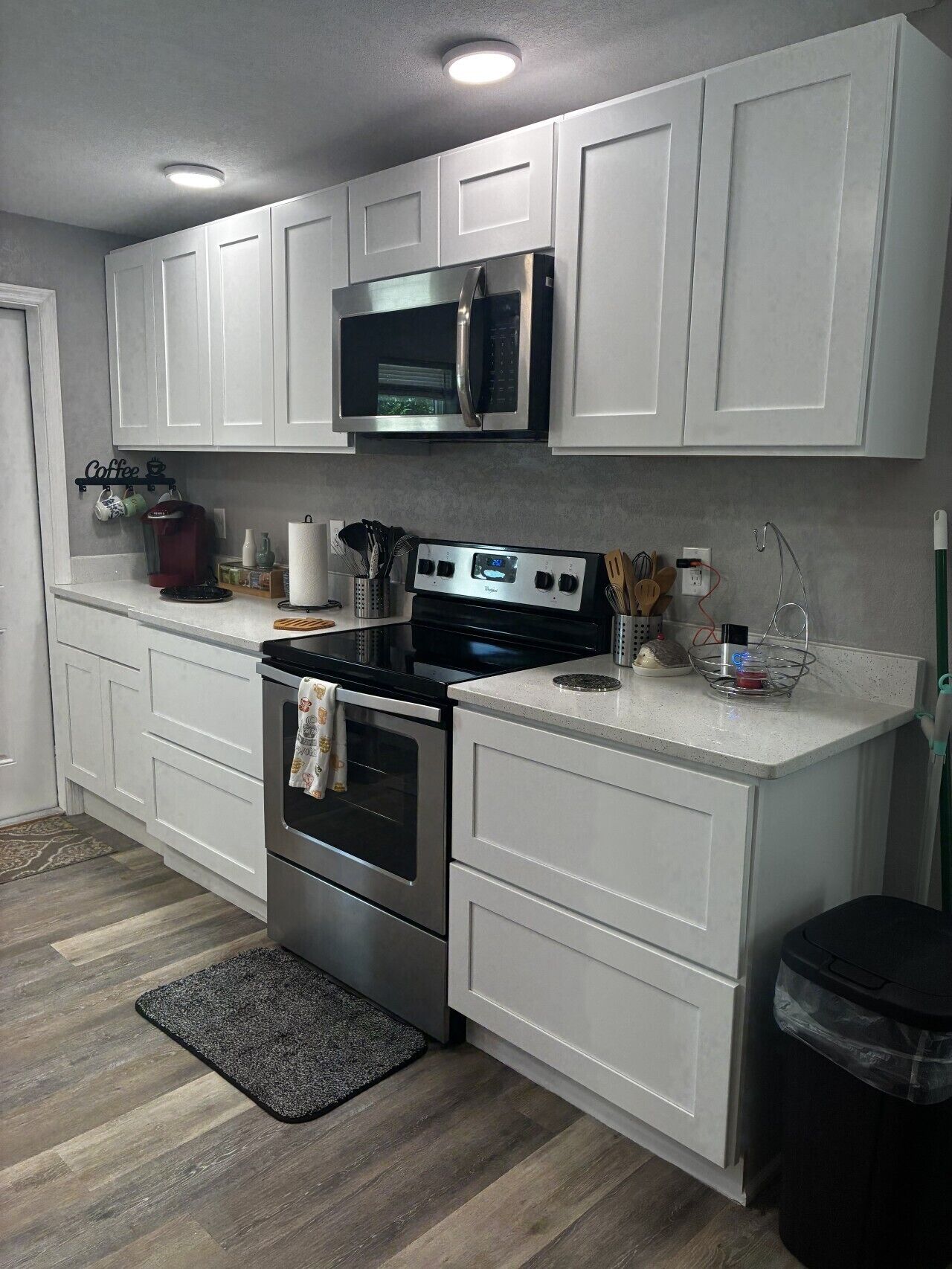 A modern kitchen with white cabinetry, stainless steel appliances, and a coffee station.