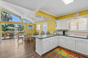 A bright kitchen with white cabinets, a central island, and a view of the outdoors. - 2BR, 2BA Beach House w/ Private Pool 11-Minute Walk to Shoreline (Panama City Beach)