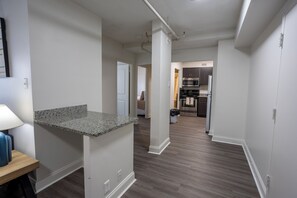 Eine moderne Küche mit dunklem Holzboden, weißen Wänden und einer Arbeitsplatte aus Granit.