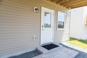 Une maison de plain-pied avec une porte d’entrée, une petite fenêtre et une véranda.