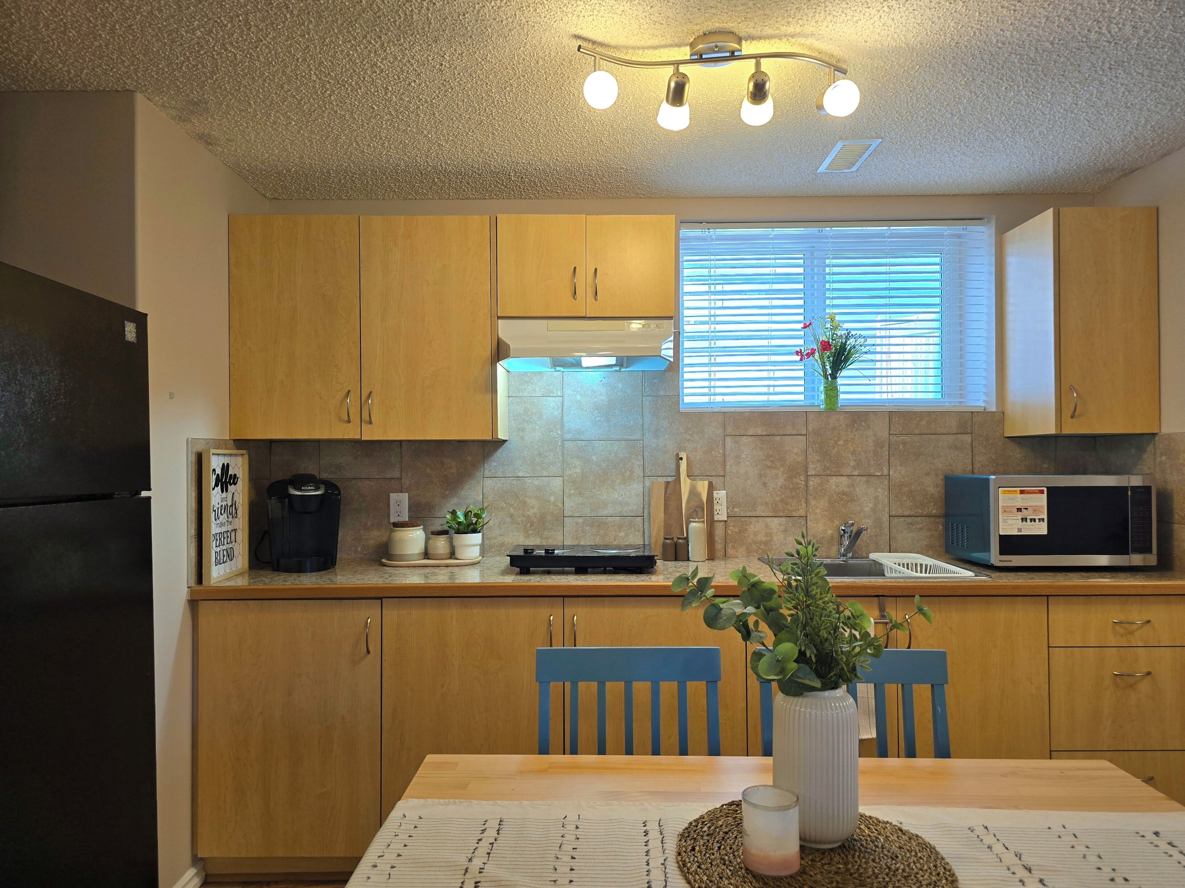 A kitchen with wooden cabinets, a microwave, a sink, and a dining table with chairs.