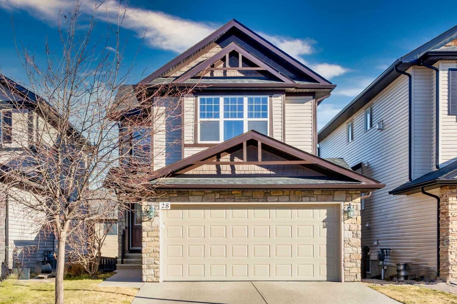 A residential house with a garage, stone foundation, and a clear sky.
