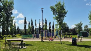 Ein Park mit Spielgeräten, einem Picknicktisch und einem Mülleimer.
