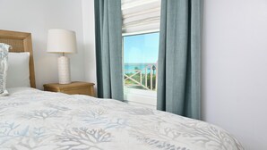 Un dormitorio con cama, mesita de noche, lámpara y ventana con cortinas.
