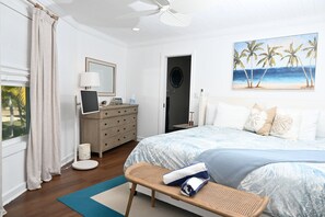 Un dormitorio con cama, cómoda, escritorio, silla, un cuadro y ventana con cortinas.