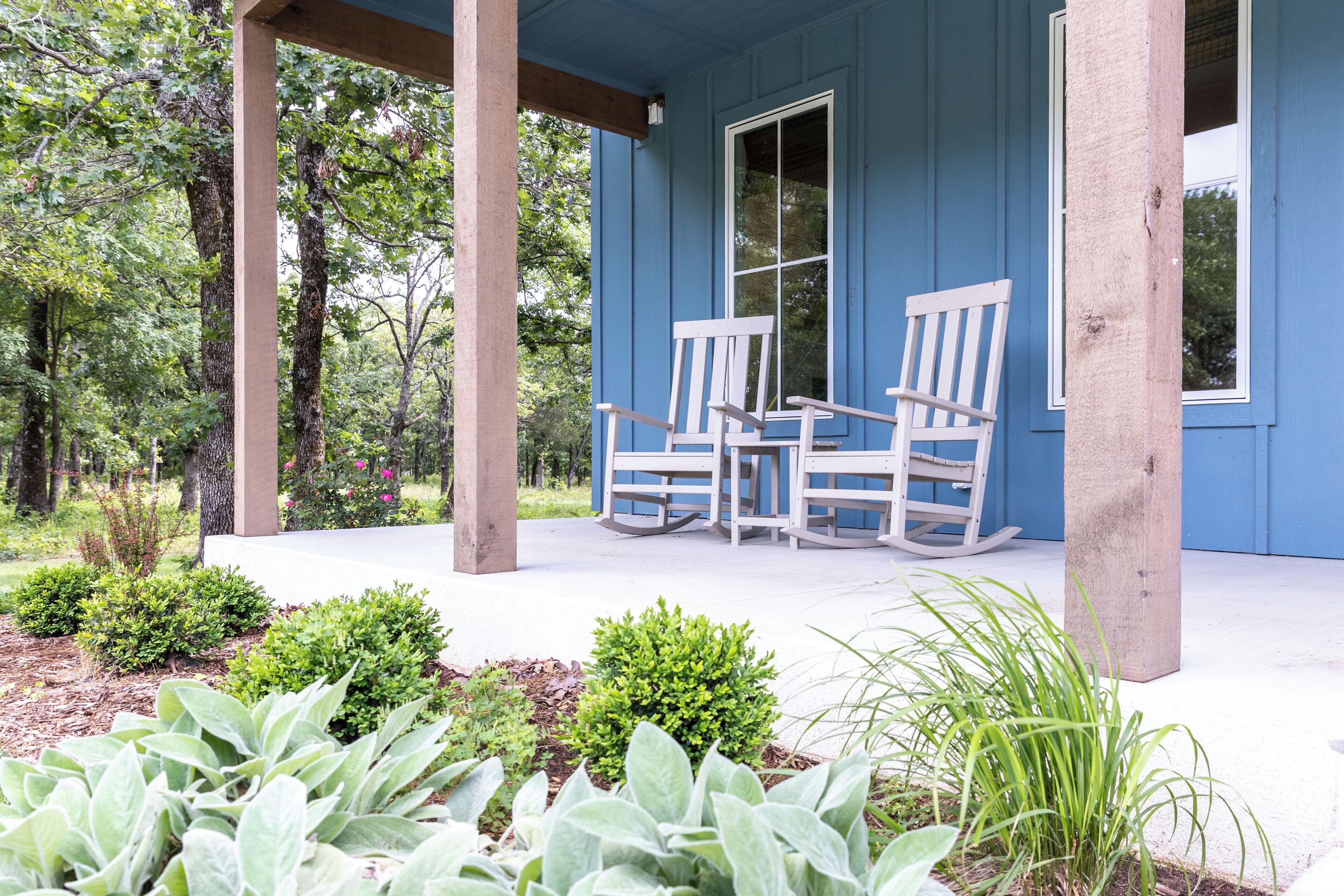 A porch with two rocking chairs, a wooden column, and a window.