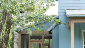 Une maison dotée d’un porche abrité, d’un mur en pierre et d’un jardin agrémenté de plantes et de fleurs.