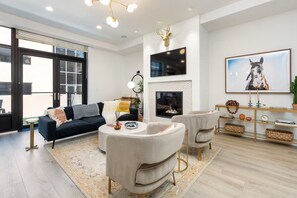 A modern living room with a sofa, armchairs, a fireplace, and a mounted deer head. - Modern Downtown Luxury Apartment Pearl & Hiking (Boulder)