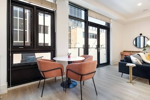 A modern living room with a round table, two chairs, a sofa, and large windows. - Modern Downtown Luxury Apartment Pearl & Hiking (Boulder)