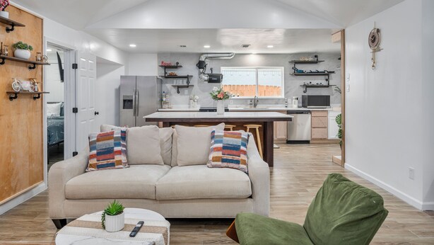 Una sala de estar moderna con un sofá, un sillón verde y una mesa de centro con un control remoto.