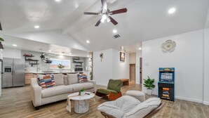 Un salón amplio con sofá, una silla, una mesa de centro y un ventilador de techo.