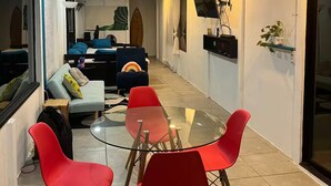 Ein modernes Wohnzimmer mit Glastisch, roten Stühlen, einer Couch und einem Deckenventilator.