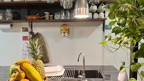 Eine Küche mit schwarzem Marmor-Arbeitsplatz, einem Edelstahl-Spülbecken und verschiedenen Küchengeräten sowie Dekorationen.