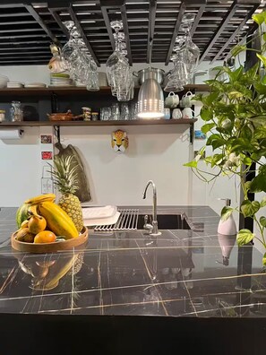 A kitchen with a black marble countertop, a stainless steel sink, and a variety of kitchenware and decorations. - Entire Downtown Home with Private Pool & A/C (Uvita)
