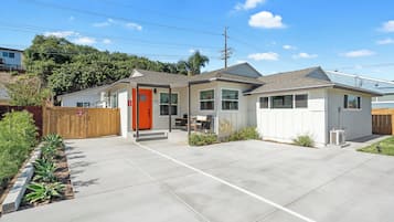Ein eingeschossiges Haus mit Veranda, einer roten Tür und einer Garage.