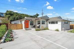 A single-story house with a front porch, a red door, and a garage.