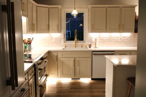 A kitchen with white cabinets, a stainless steel range, and a window with a view of the outside. - Private Oasis with Luxury Heated Pool, Hot Tub & 100" TV (Clive)
