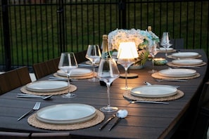 A dining table set for a meal with plates, cutlery, and wine glasses. - Private Oasis with Luxury Heated Pool, Hot Tub & 100" TV (Clive)