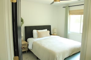 A neatly made bed with white bedding, a dark headboard, and a bedside lamp. - Private Oasis with Luxury Heated Pool, Hot Tub & 100" TV (Clive)