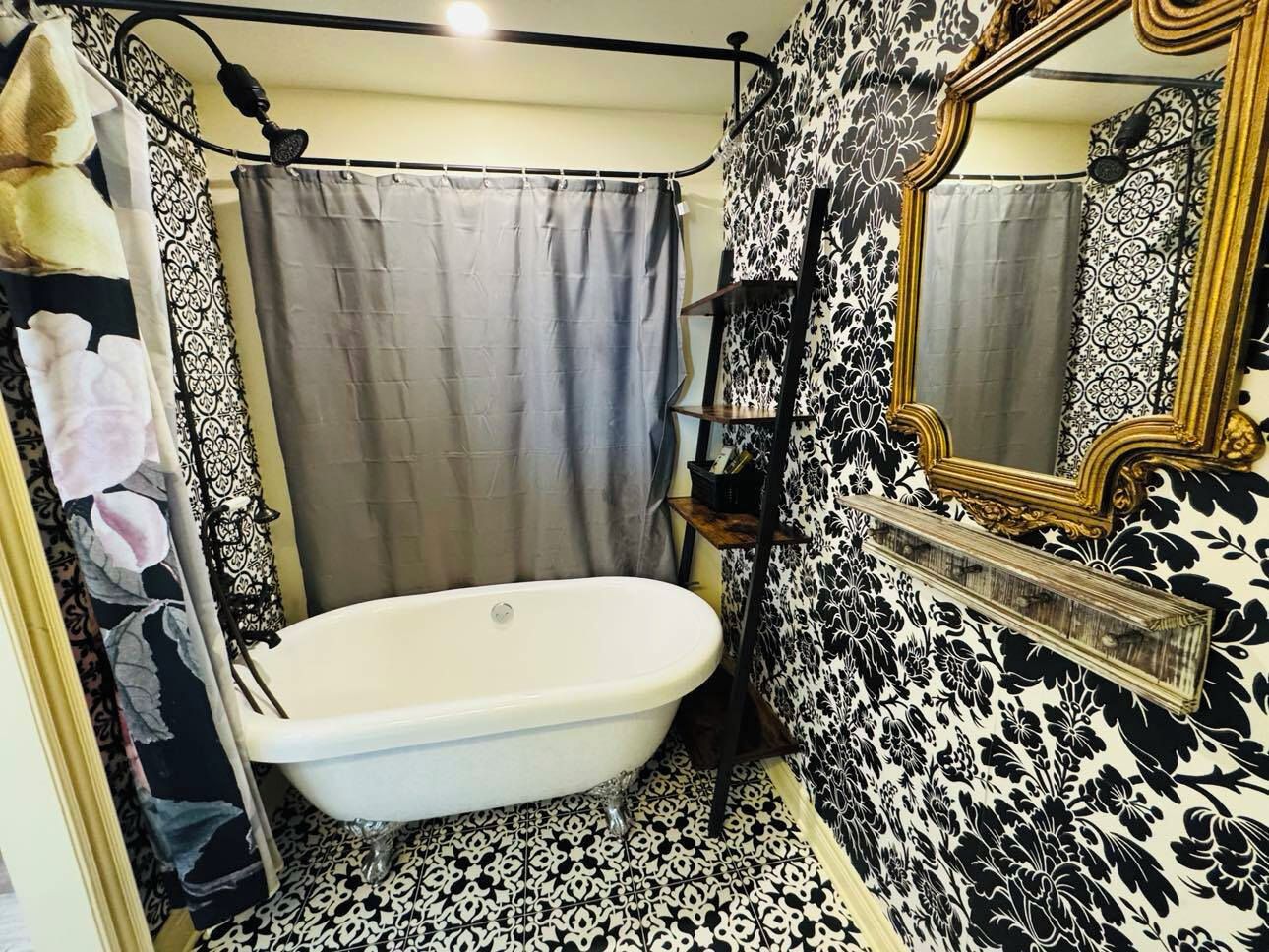 A bathroom with a bathtub, a shower curtain, and a mirror.