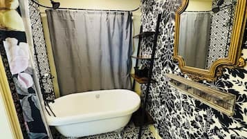 A bathroom with a bathtub, a shower curtain, and a mirror.