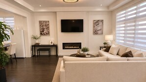 Een moderne woonkamer met een bank, een open haard, een televisie en kunst aan de muren.