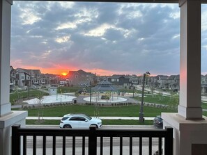 Un barrio residencial con casas, un parque infantil y un atardecer.