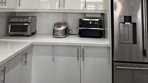 Een moderne keuken met witte kastjes, een roestvrijstalen koelkast, een toasteroven en een koffieapparaat.