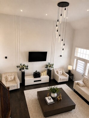 A modern living room with a flat-screen TV mounted on the wall, a dark coffee table with decorative items, and two white sofas. - Newly furnished luxury home in Oakville, entire home”. near Oakville Hospital. (Oakville)