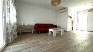 A modern living room with a red sofa, a white sideboard, and a wooden floor. - Beautiful Beach House with a 40 m² Sunny Terrace and a 5-Minute Walk to the Beach (Torrevieja)